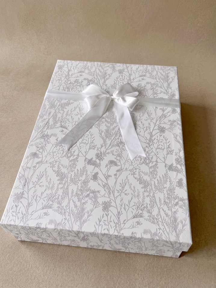 Closed WedBox preservation box with silver floral lining paper and a white satin bow